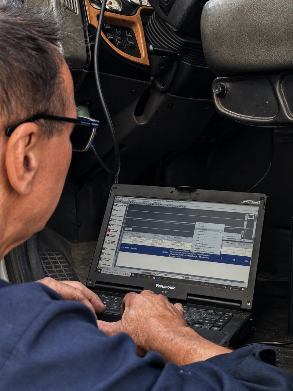 Technician using a rugged laptop to diagnose a heavy-duty truck at Big Truck & Trailer Repair in Park City, Illinois